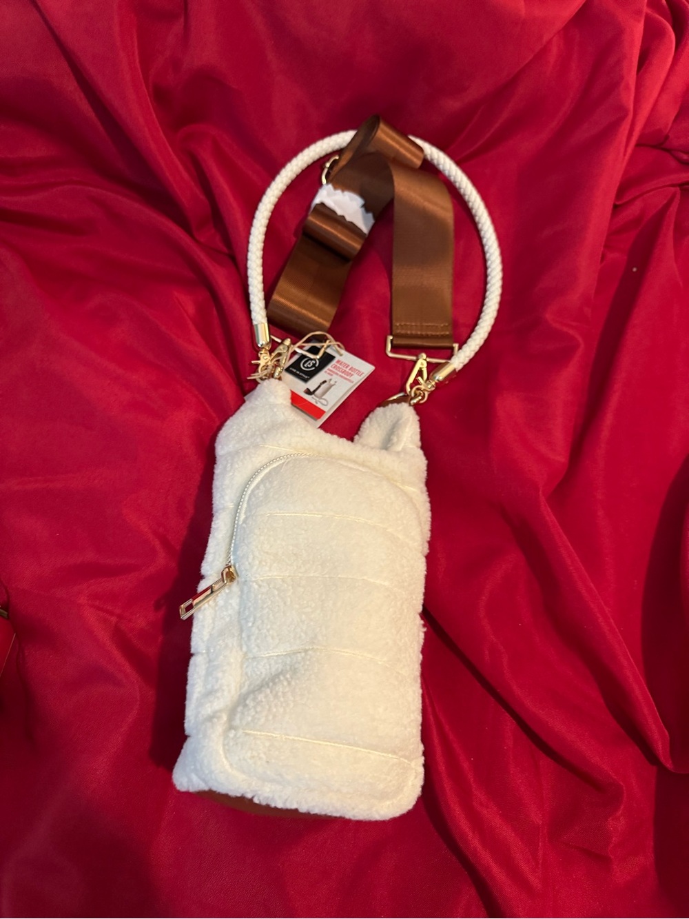 The White Sherpa Crossbody Phone Bag & Water Bottle Bag features a brown strap